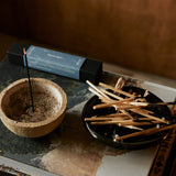 Close-up of lit Shinrin-Yoku incense stick creating aromatic smoke in a serene indoor environment