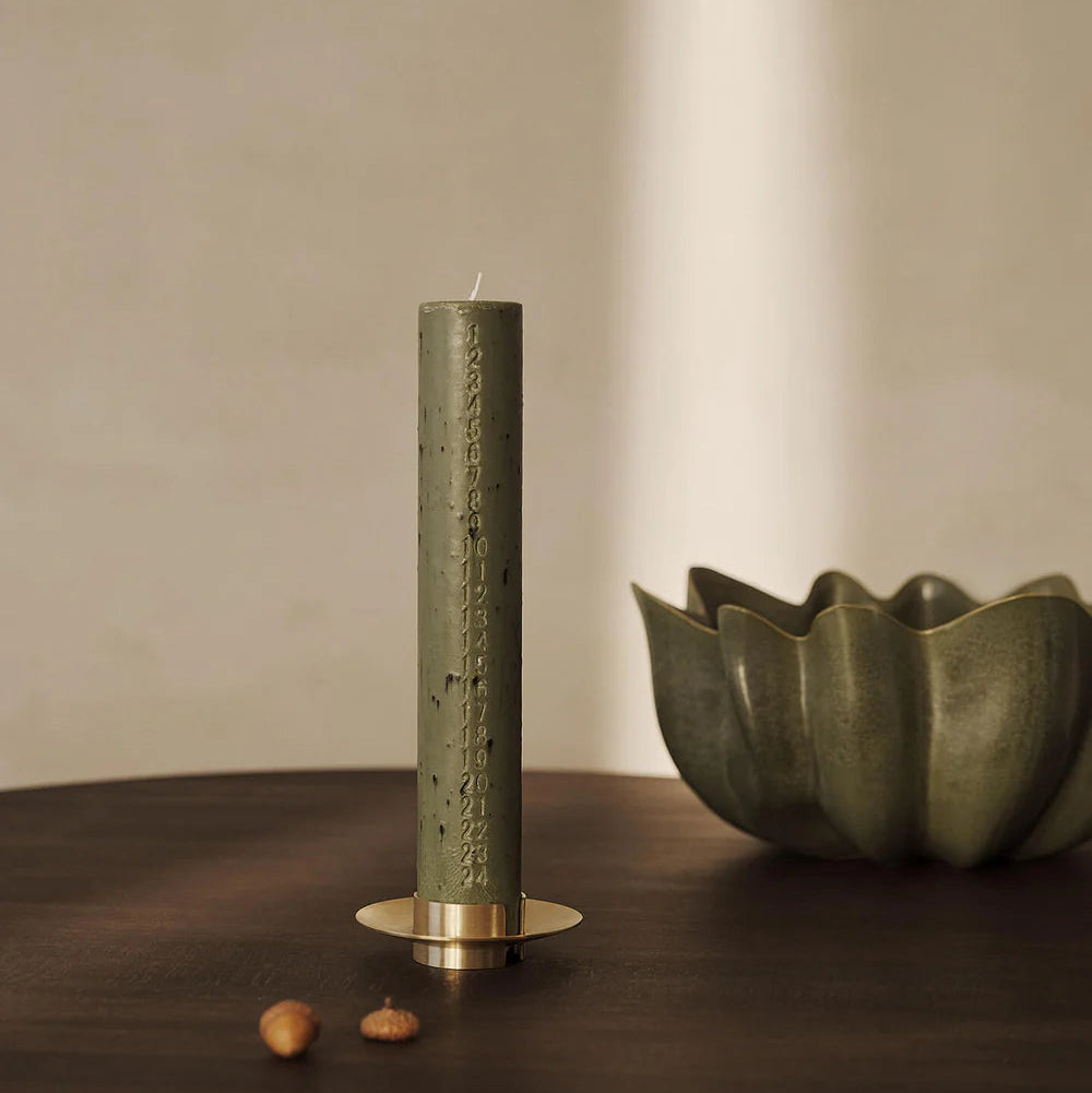 Mura Advent Candle, Artichoke Green by ferm LIVING, lit on a dark table