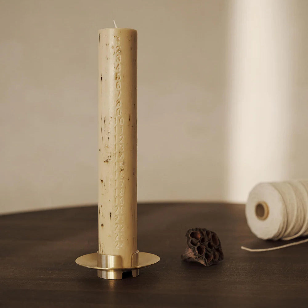 Block Candle Holder, Brass by ferm LIVING, holding a tall taper candle