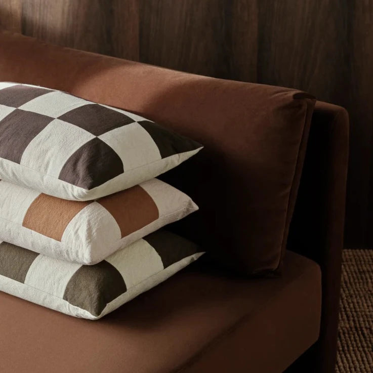Fold Patchwork Cushion, Sugar Kelp by ferm LIVING, on a brown sofa