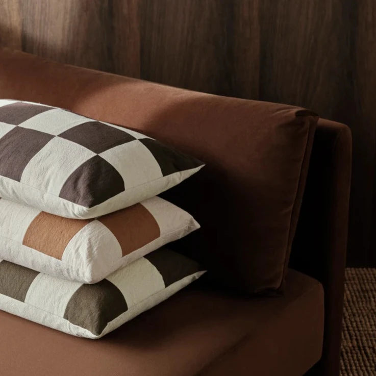 Fold Patchwork Cushion, Coffee by ferm LIVING, on a brown sofa