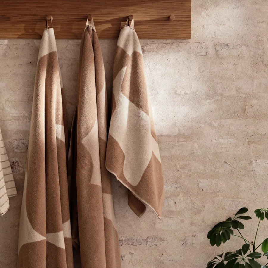 Ebb Bath Towel, Sand/Off-White by ferm LIVING, hanging on hooks