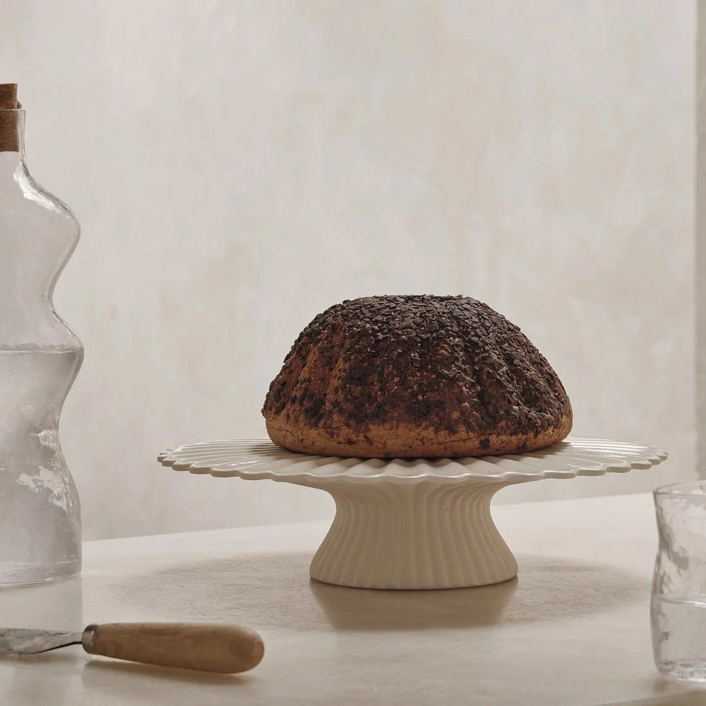 Fountain Cake Stand, Off White by ferm LIVING, holding a bundt cake