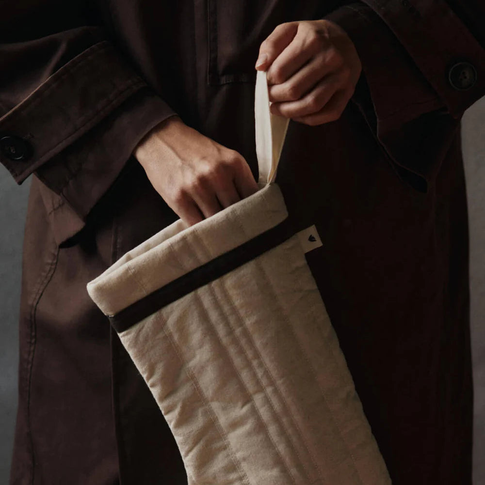 Person holding a quilted cream Christmas stocking