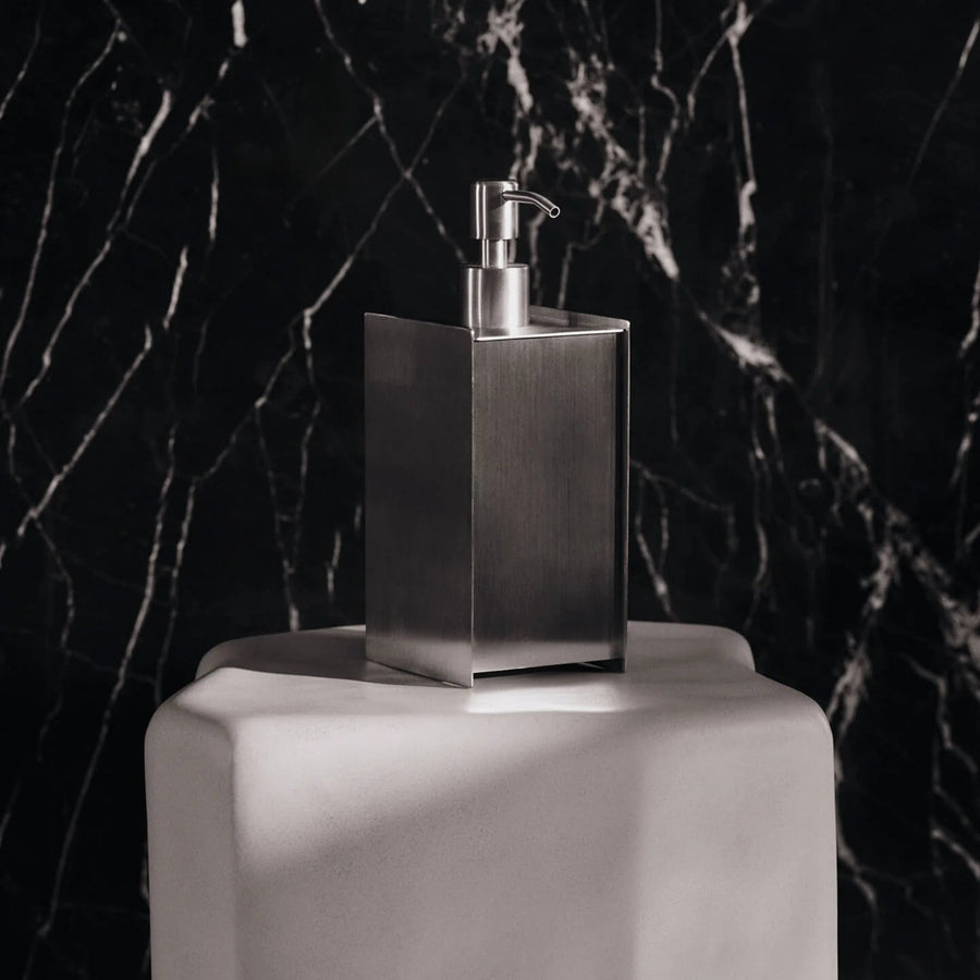 Sama Soap Dispenser, Brushed Stainless Steel by ferm LIVING, against dark marble