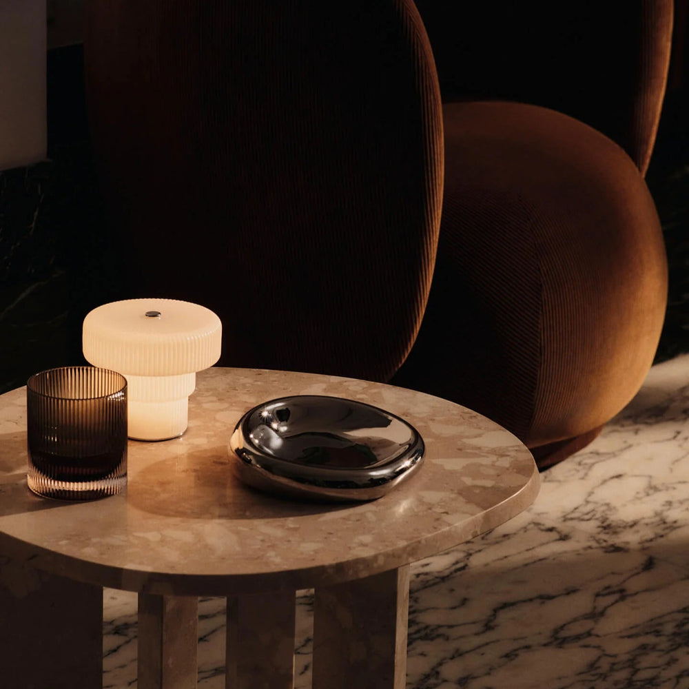 Ripple Portable Lamp, Small, White by ferm LIVING, lit on a side table