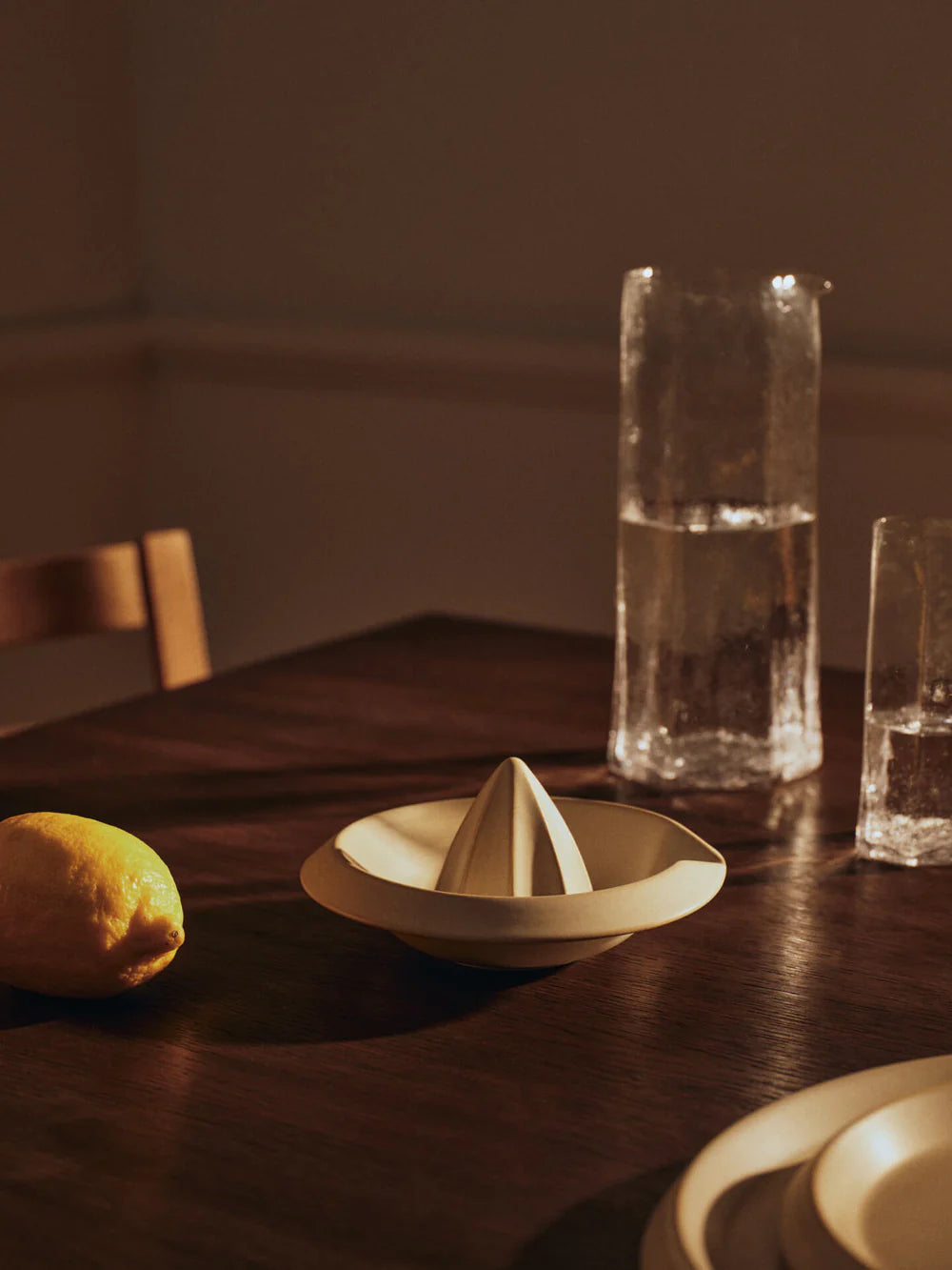 Erena Citrus Juicer, Cream by ferm LIVING, on a dark table with a lemon