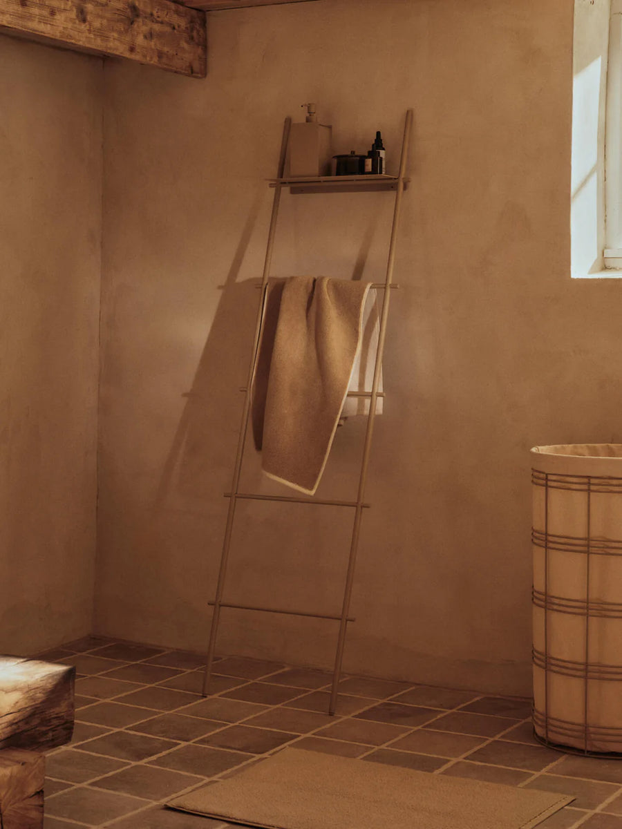 Dora Towel Ladder, Cashmere by ferm LIVING, holding a towel in a bathroom