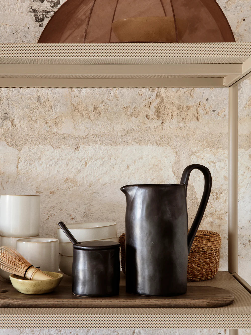 Rustic kitchen shelf with a jug and cooking pots under an arched alcove