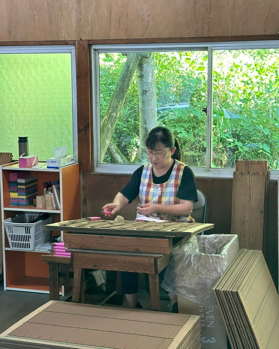 Woman sitting at a desk packaging up incense into bundles