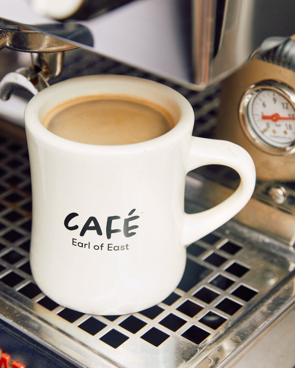 Americano Scented Candle in Mug, 300ml by Earl of East, beside an espresso machine