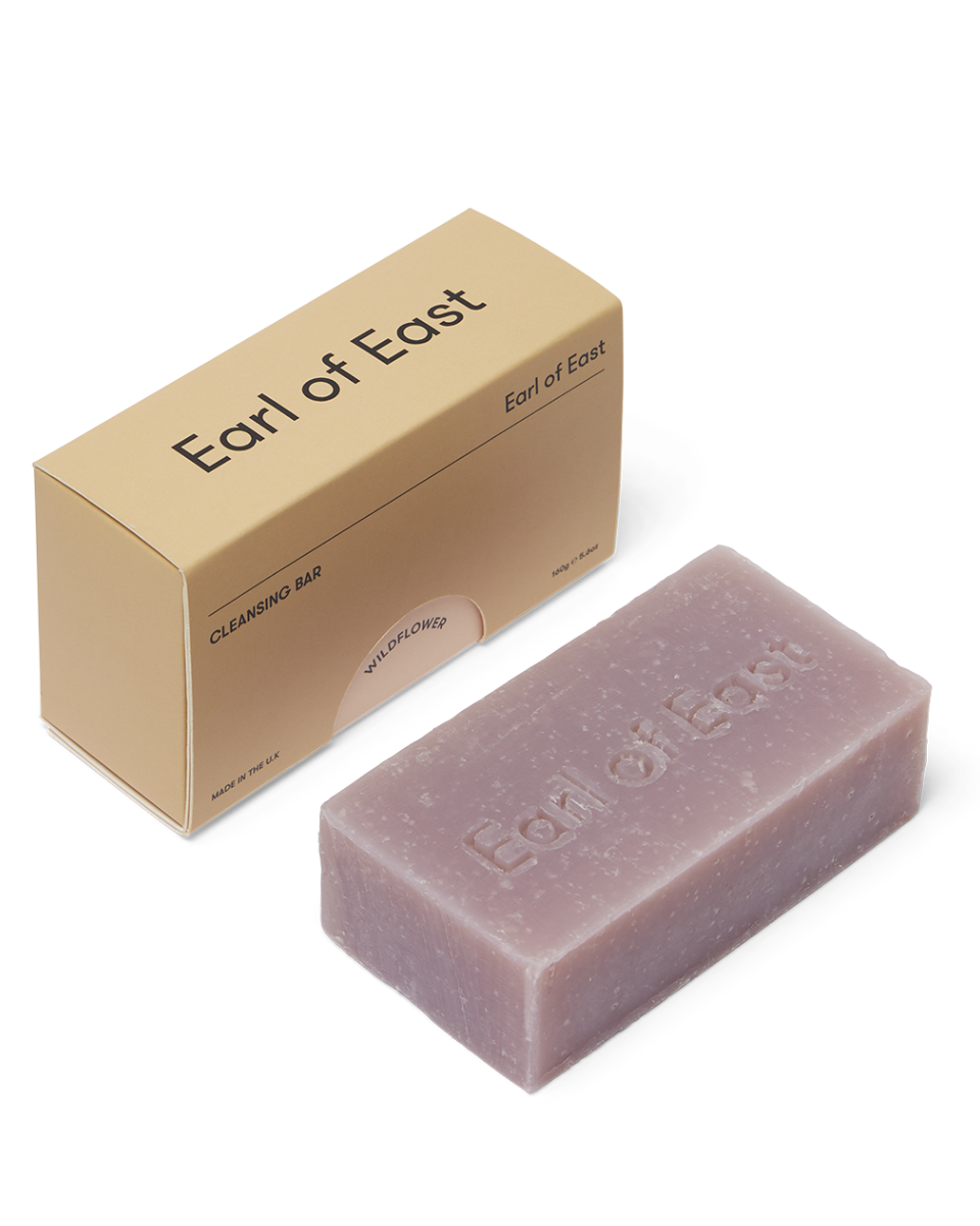 A soap bar next to its packaging box, with the Earl of East brand visible on both the bar and the box.