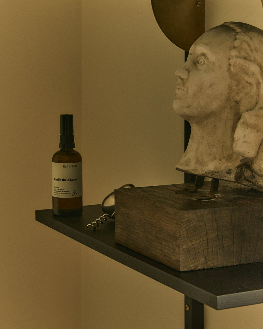 Jardin de la Lune Home Mist, 100ml by Earl of East, on a shelf beside a stone bust