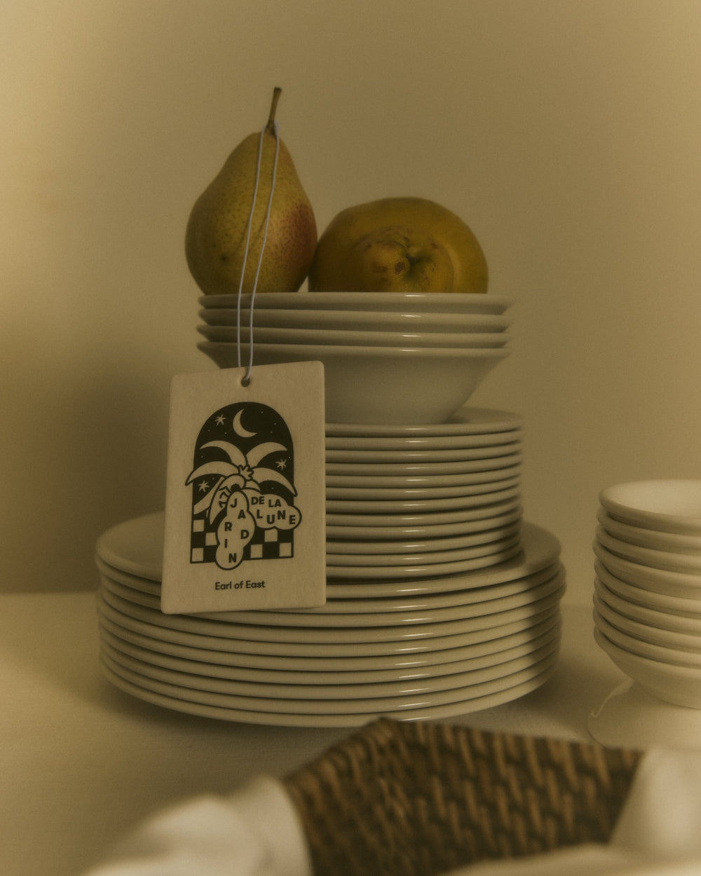 Jardin de la Lune Air Freshener by Earl of East, hanging beside stacked plates and pears
