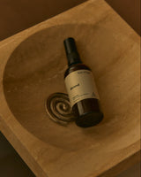 A Strand Home Mist resting in a carved stone basin.
