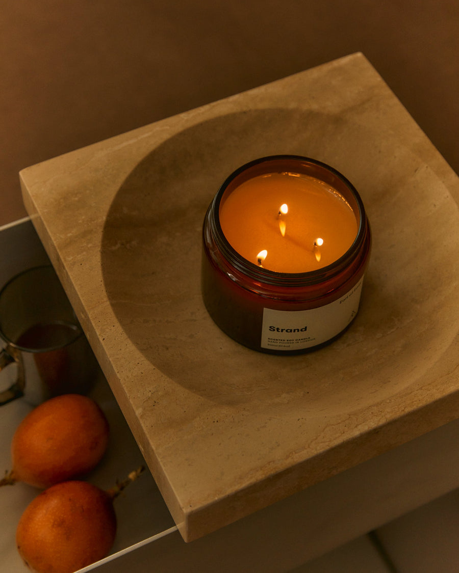 Strand Large Scented Candle, 500ml by Earl of East, lit on a wooden board