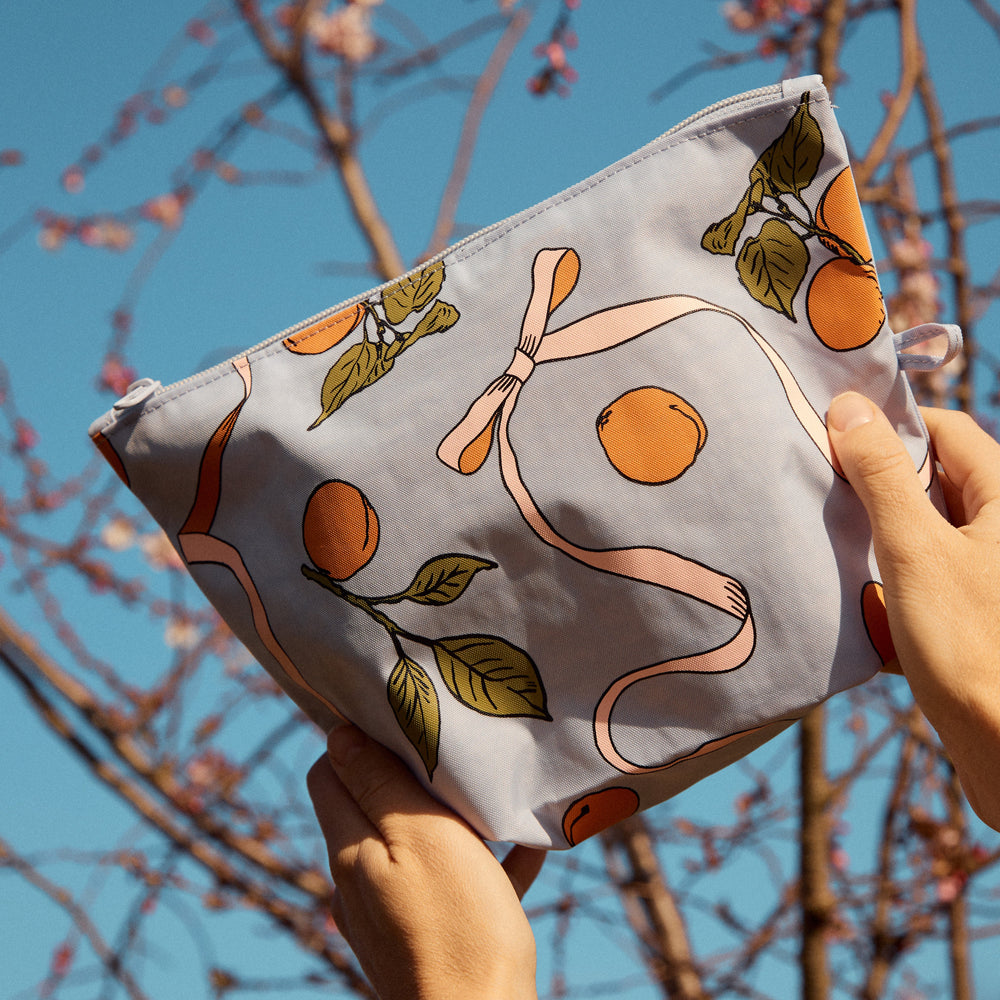 Go Pouch Set, Get Ready With Me by Baggu, held up among blossom branches