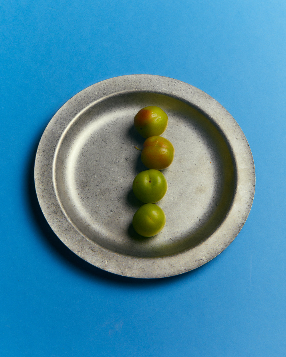 Small Plate, Vintage Stainless Steel by Earl of East, holding olives on blue