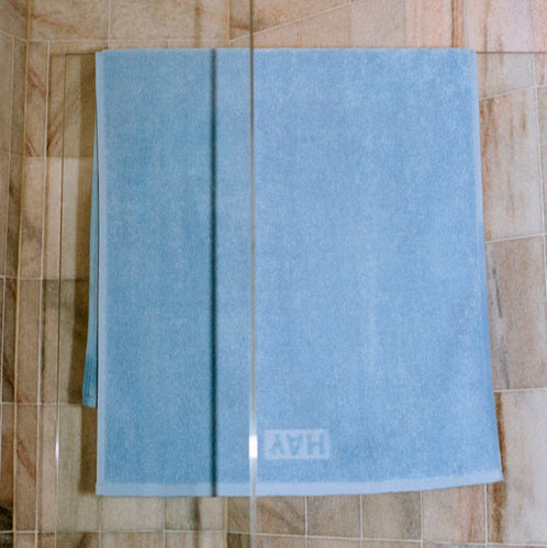 Mono Bath Towel, Sky Blue by HAY, hanging on a rail