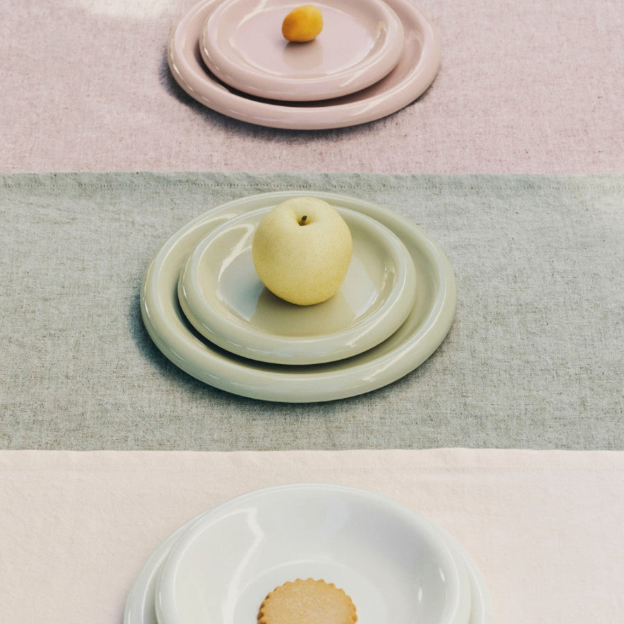 Barro Plate Set of Two, Ø24, Pistachio by HAY, stacked on a pink and green backdrop