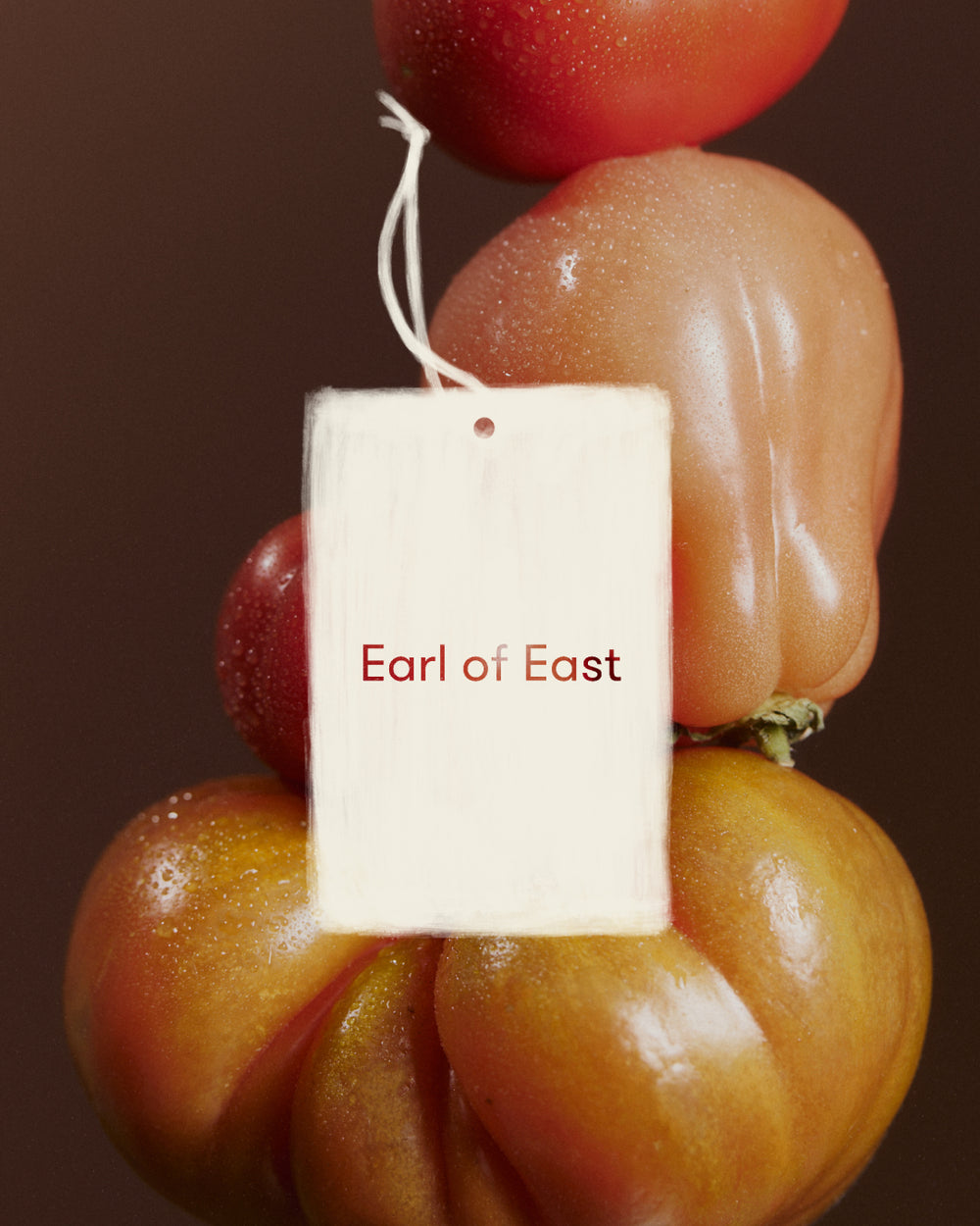 Greenhouse Air Freshener by Earl of East, hanging against stacked heirloom tomatoes