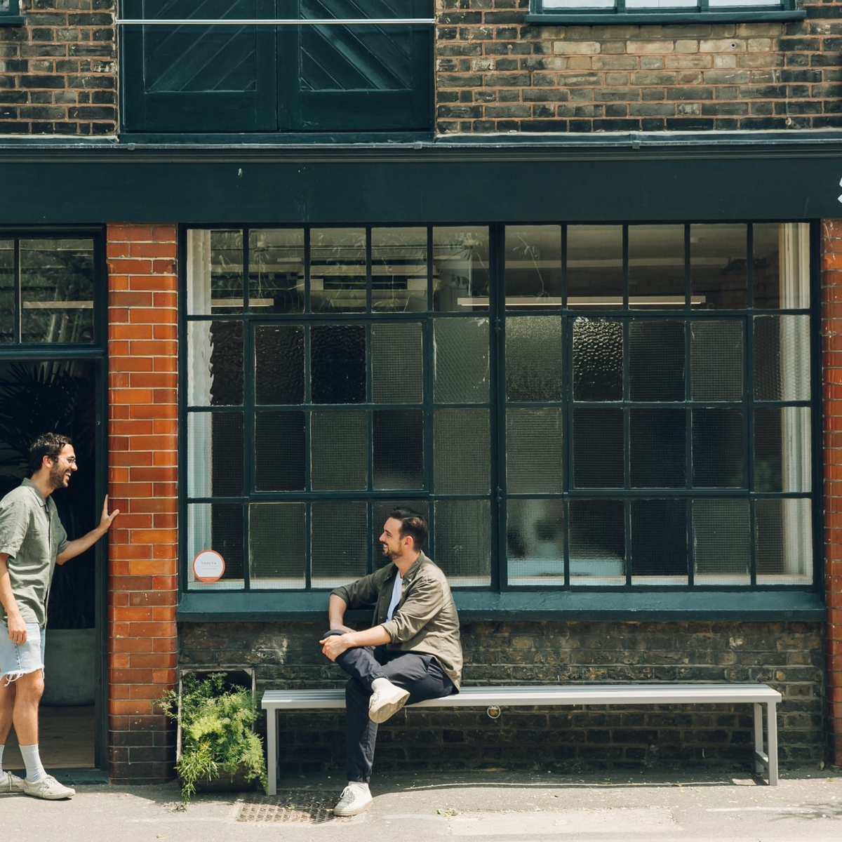 Two men sitting on a bench outside an Earl of East shop