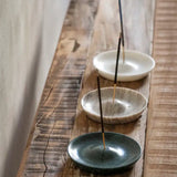 Incense sticks in marble holders on a wooden surface with smoke rising.