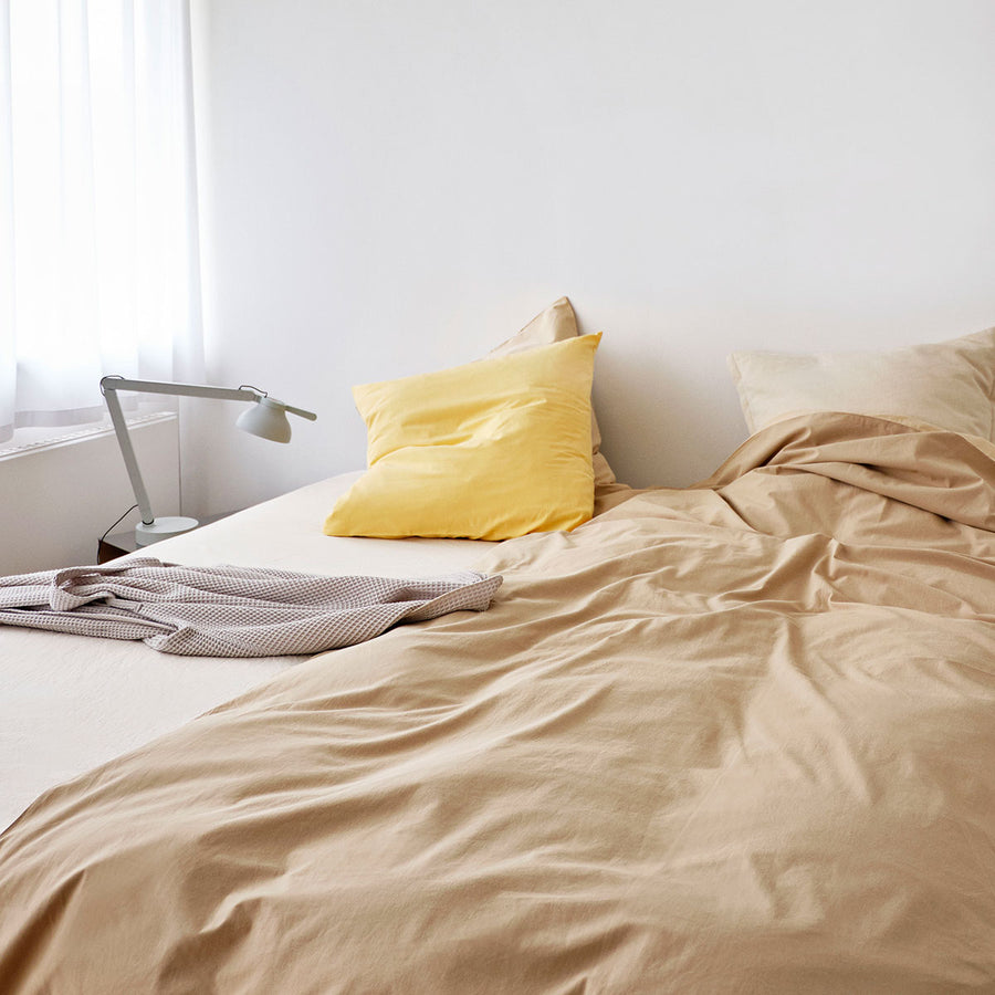 Duo Duvet Cover, 200 x 200, Cappuccino by HAY, on an unmade bed