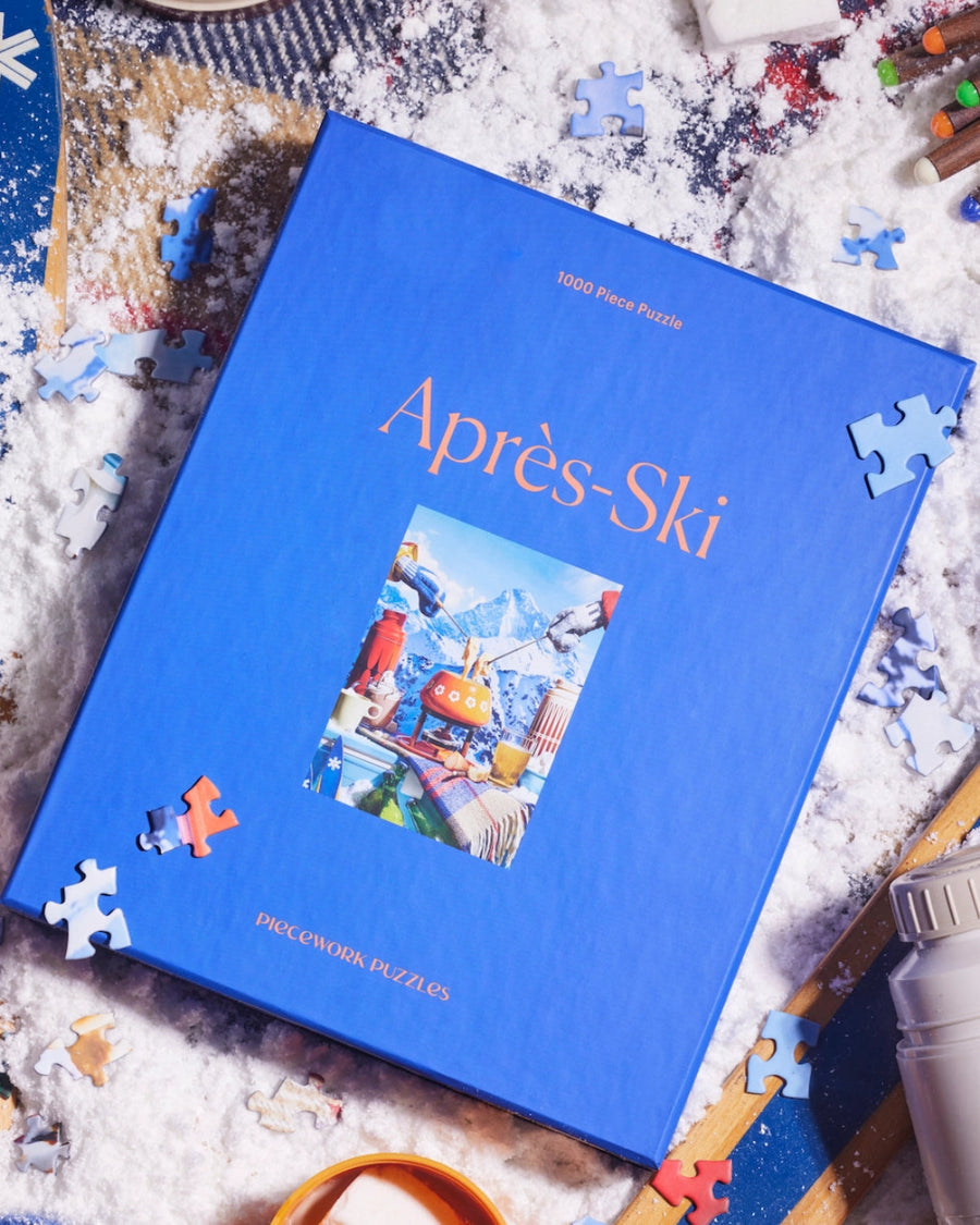 Piecework Après-Ski jigsaw puzzle box with scattered pieces
