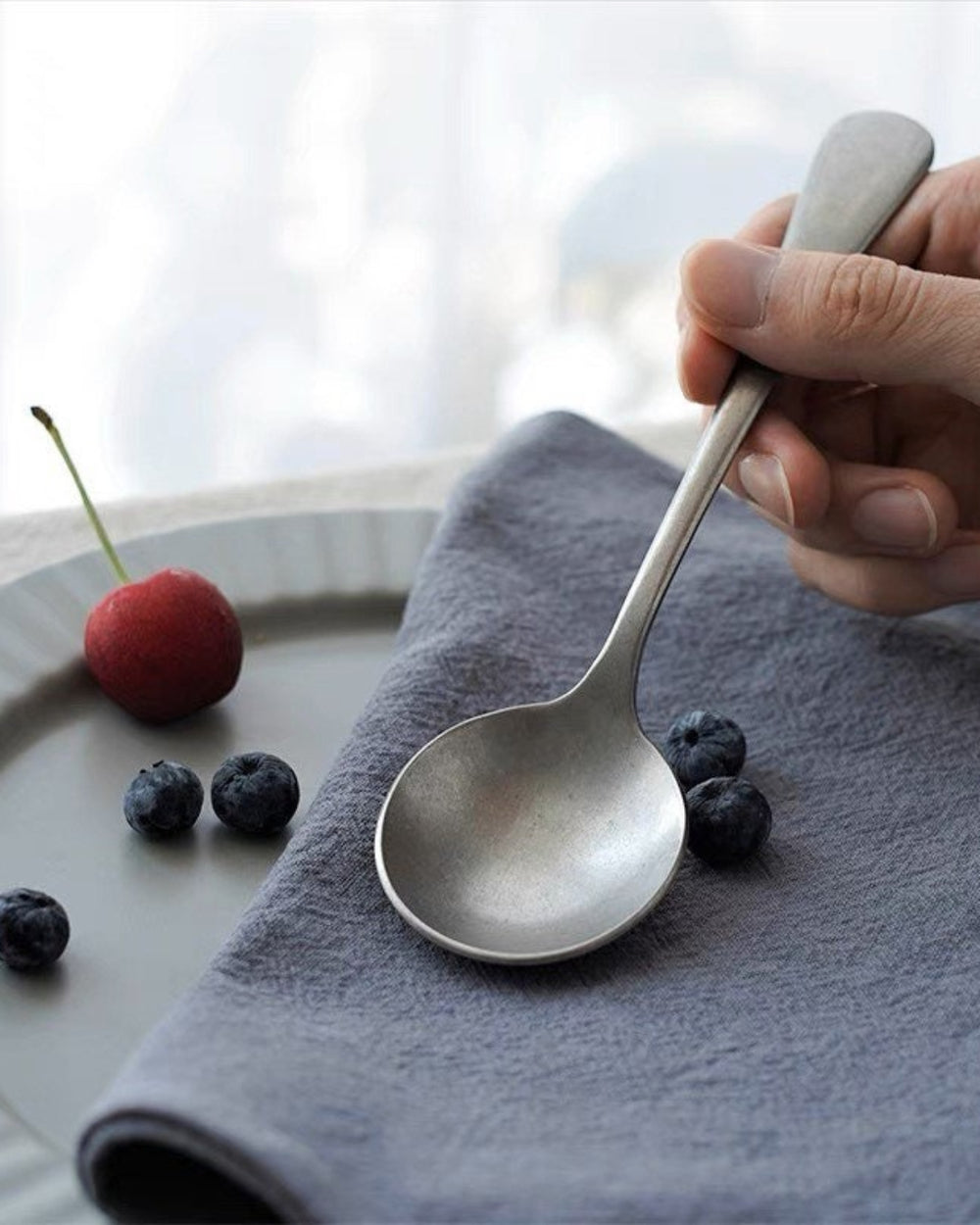 Stonewashed Stainless Steel Cutlery by Gohobi, with a cherry on a grey napkin