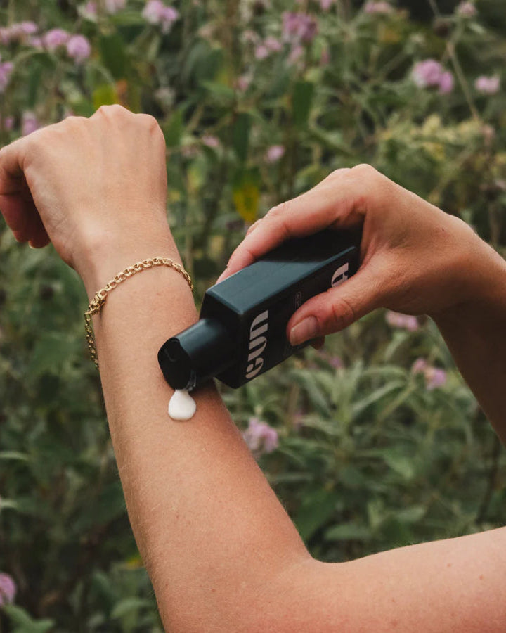 Body Milk Spf 30, 100mL by Gun Ana, being applied to an arm outdoors