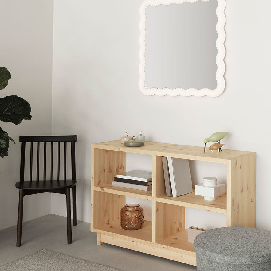 Fyr Bookcase, Pine, Low by Normann Copenhagen, in a room with a wavy mirror