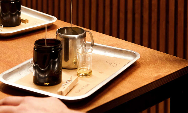 Wooden tray with metal pouring jugs on a counter in warm light