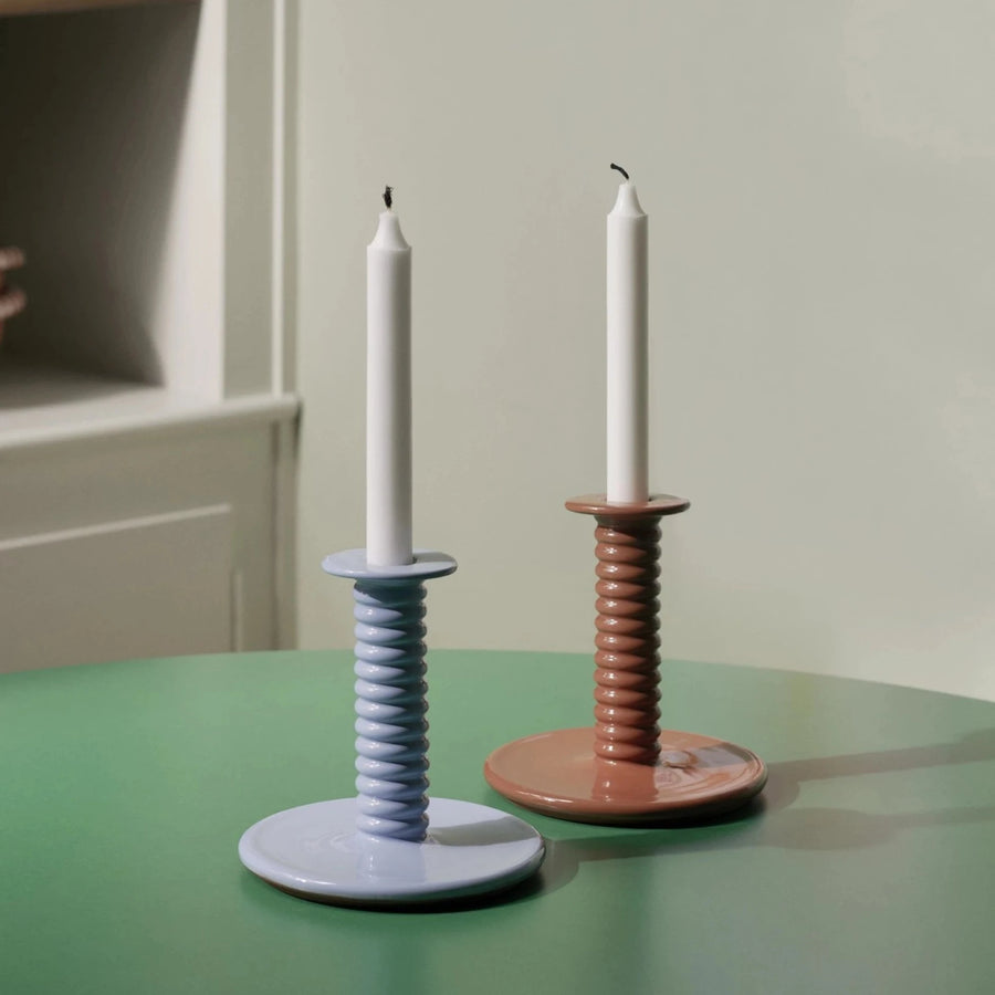 Barro Candle Holder, Light Blue by HAY, holding white candles on a green table