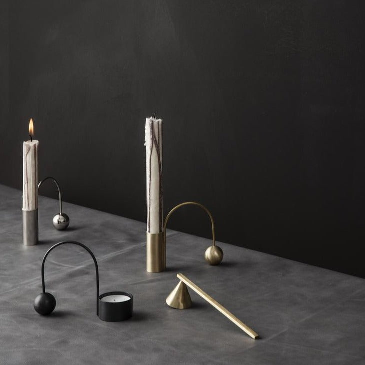Brass Extinguisher by ferm LIVING, beside a smoking candle