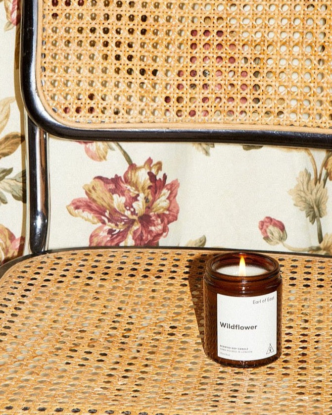 Wildflower Scented Candle, 170ml by Earl of East, on a cane chair against floral fabric